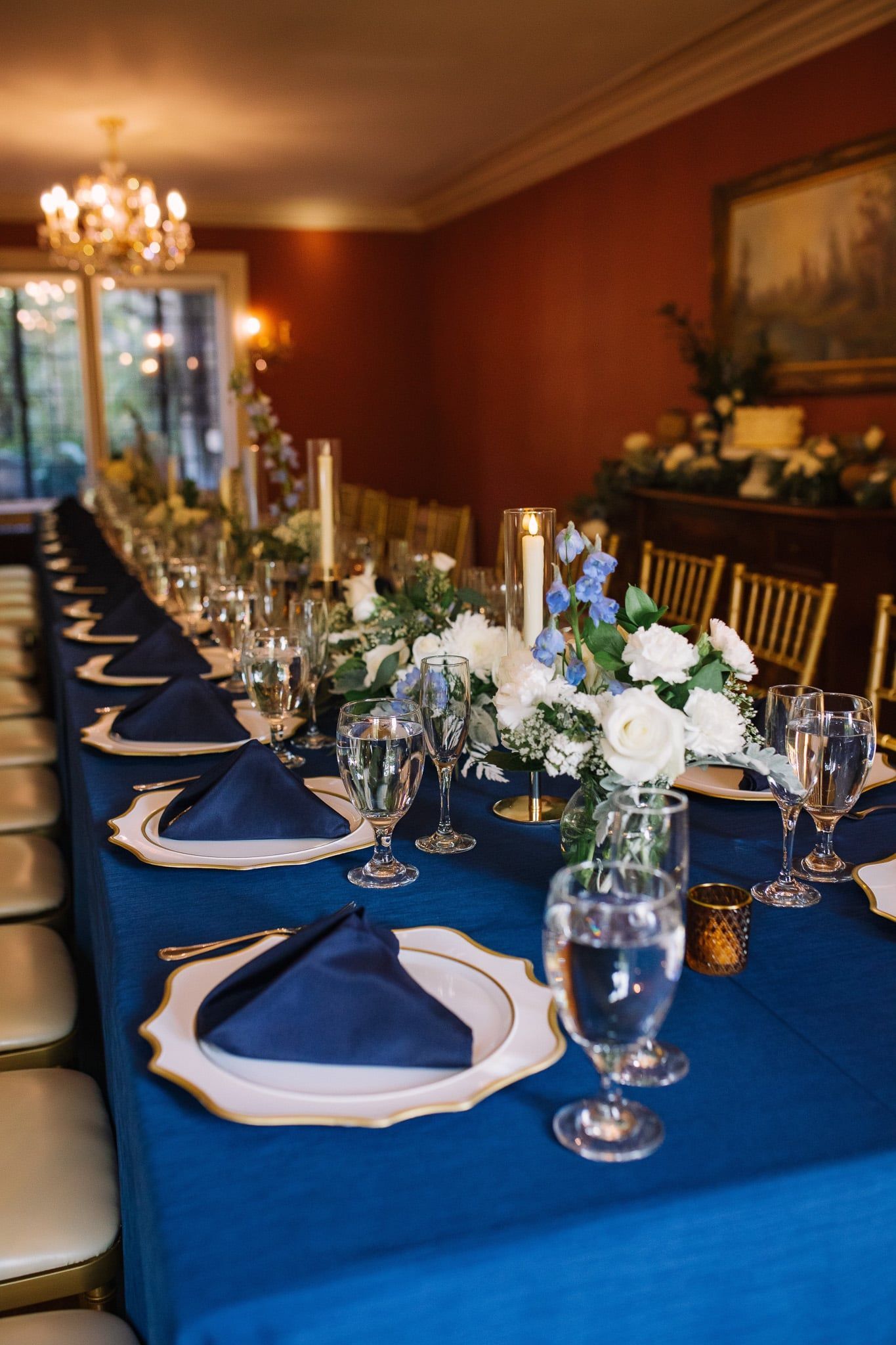 A long table with plates , glasses , napkins and flowers on it.