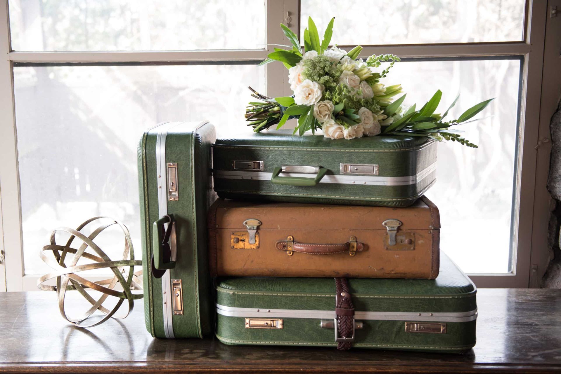Three green suitcases are stacked on top of each other on a table.