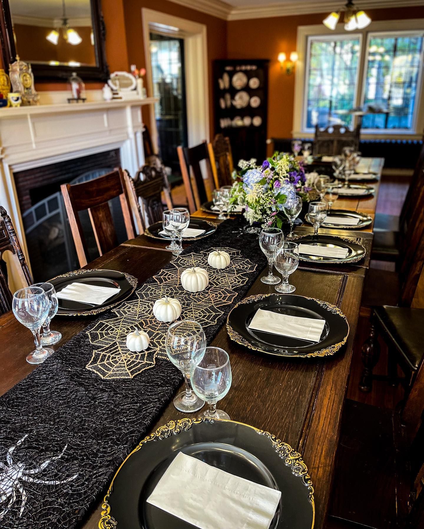 A long table with plates , glasses , napkins and pumpkins on it.