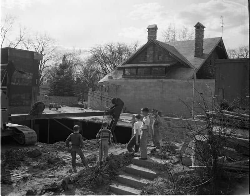 A black and white photo of a construction site with a house in the background