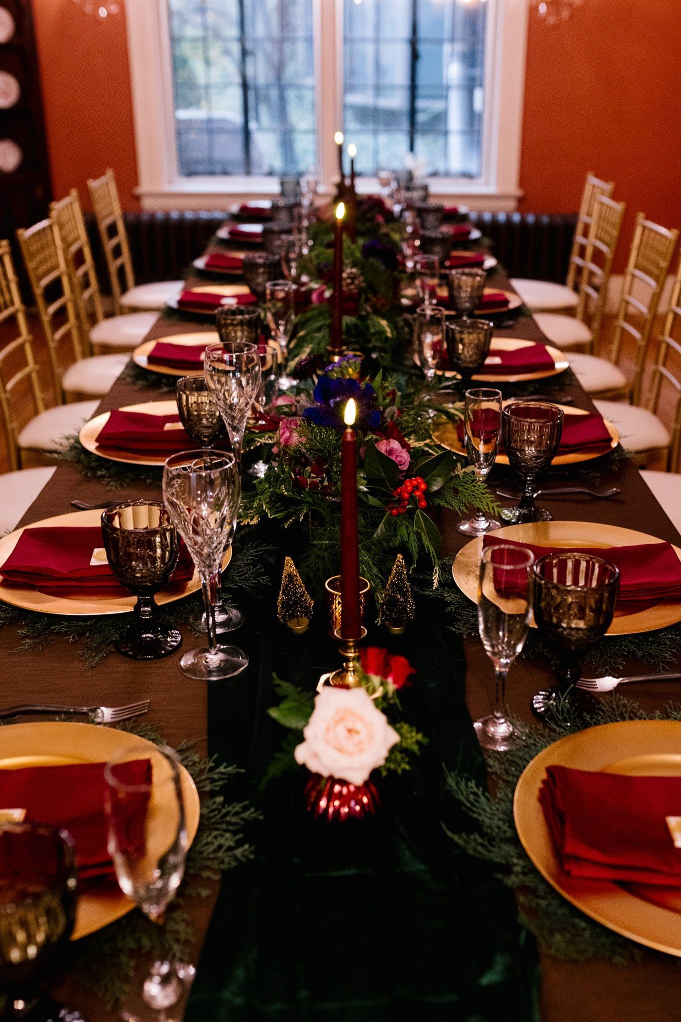 A long table set for a dinner party with plates , glasses , napkins and candles.