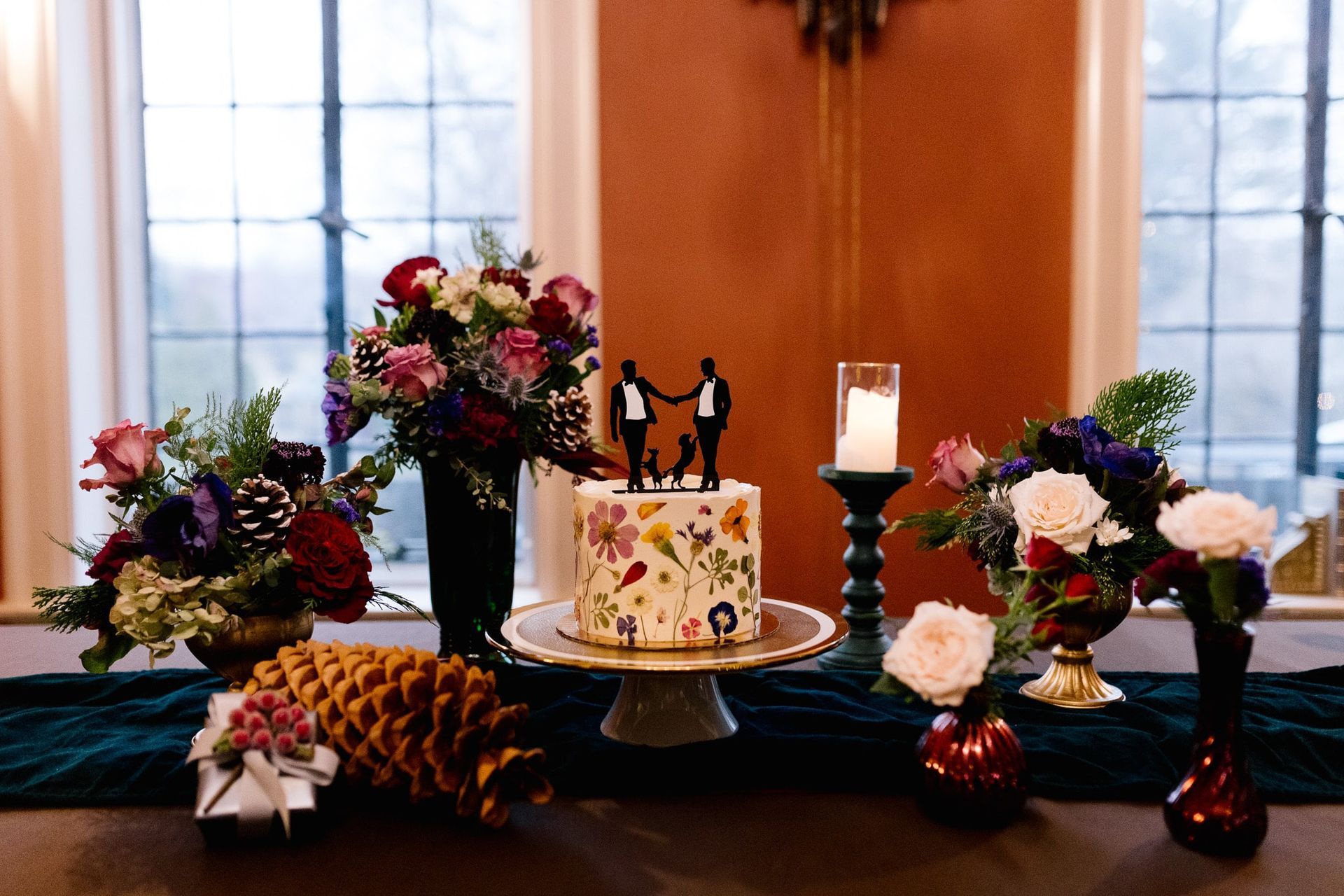 A table with a cake , candles , and flowers on it.