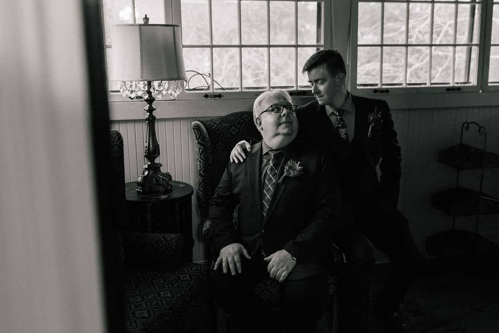 A man in a suit is sitting next to an older man in a chair.