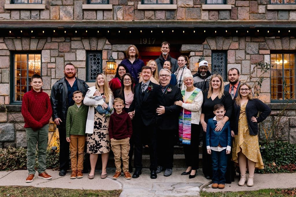 A large family is posing for a picture in front of a stone building.