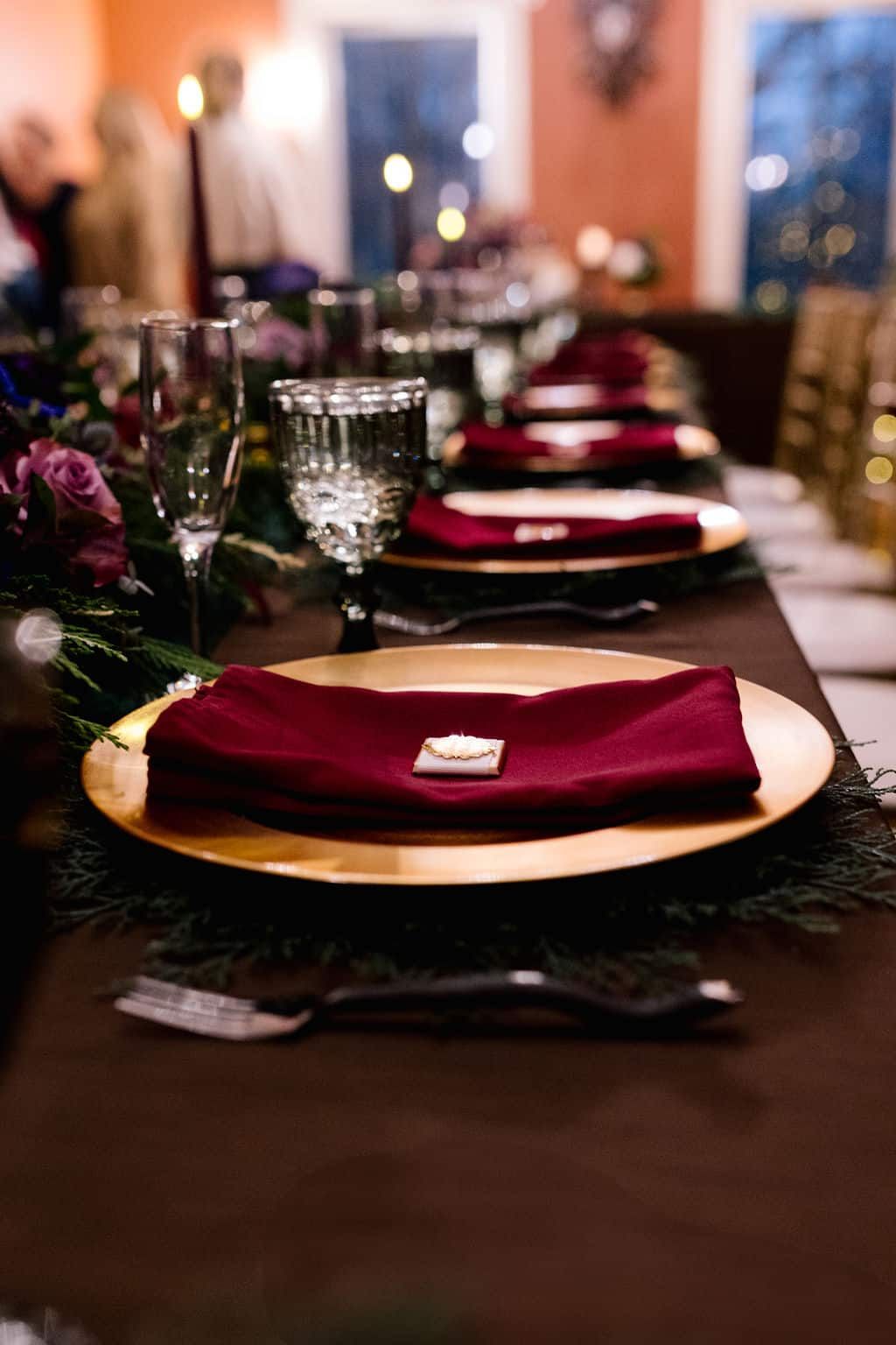 A long table set for a dinner party with plates , napkins , glasses and silverware.