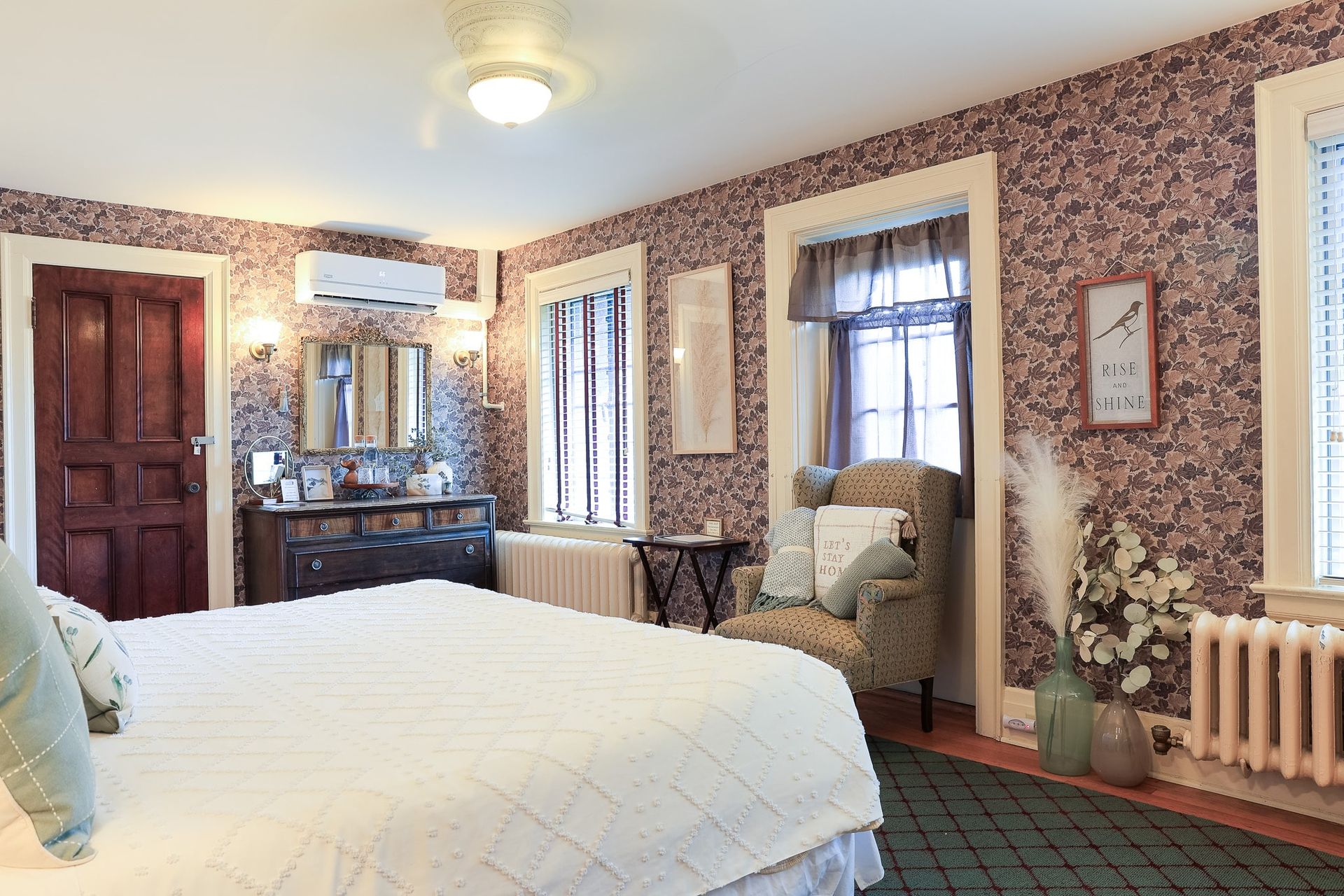 A bedroom with a bed , chair , dresser and window.