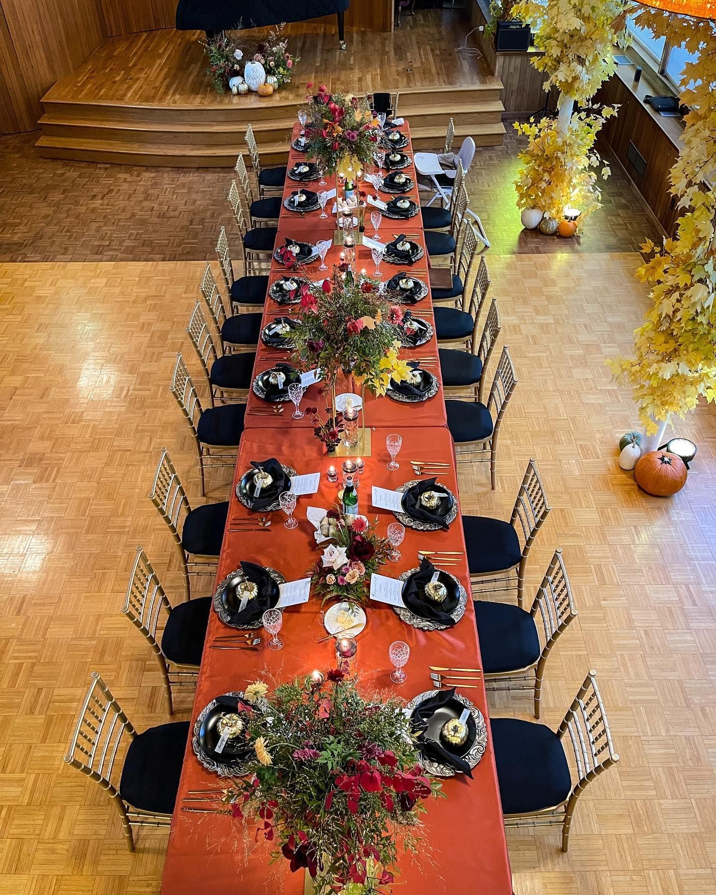 A long table with plates , utensils , and flowers on it.
