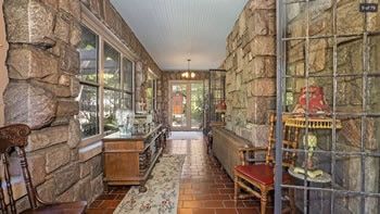 A long hallway with a stone wall and a glass door leading to the front door.