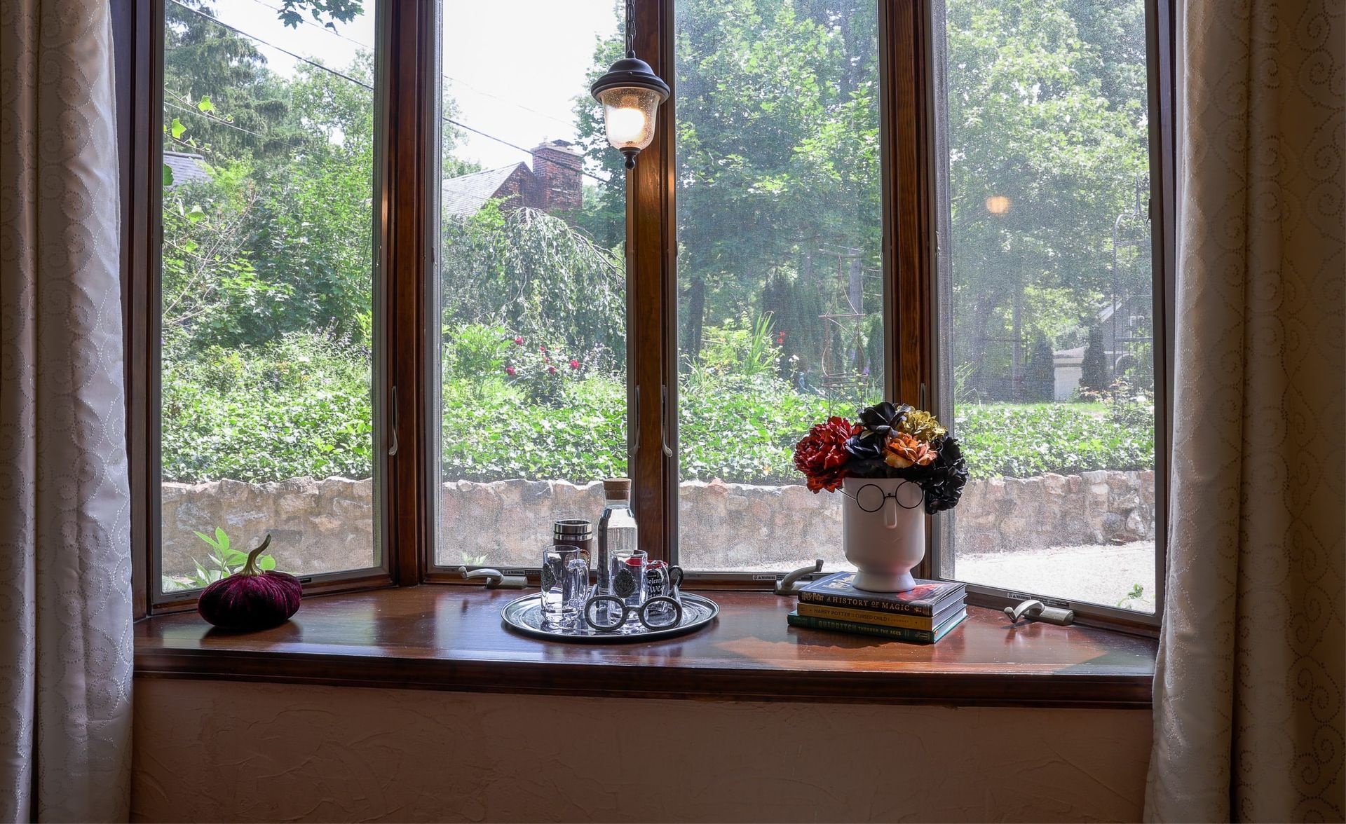 A window sill with a vase of flowers and a lamp on it.