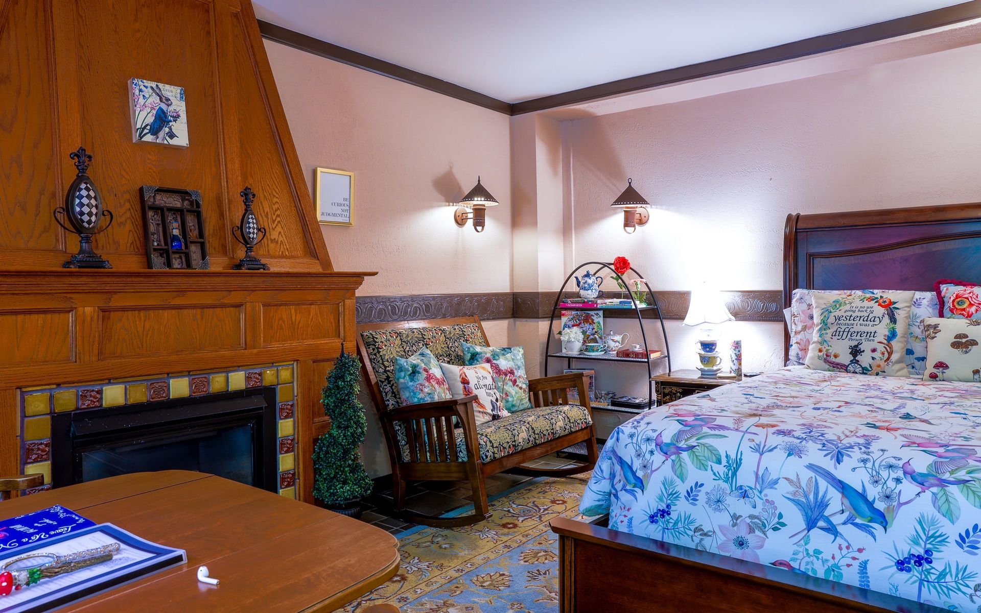 A bedroom with a bed , chair , table and fireplace.