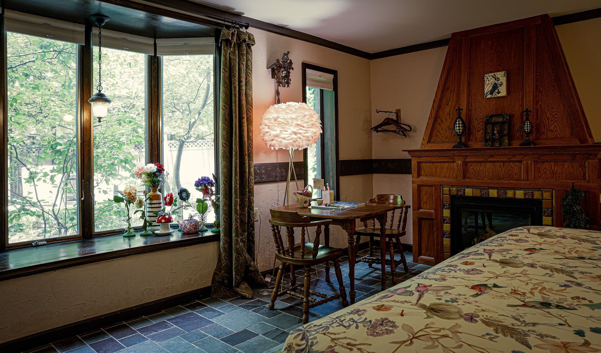 A bedroom with a fireplace , table , chairs and a large window.