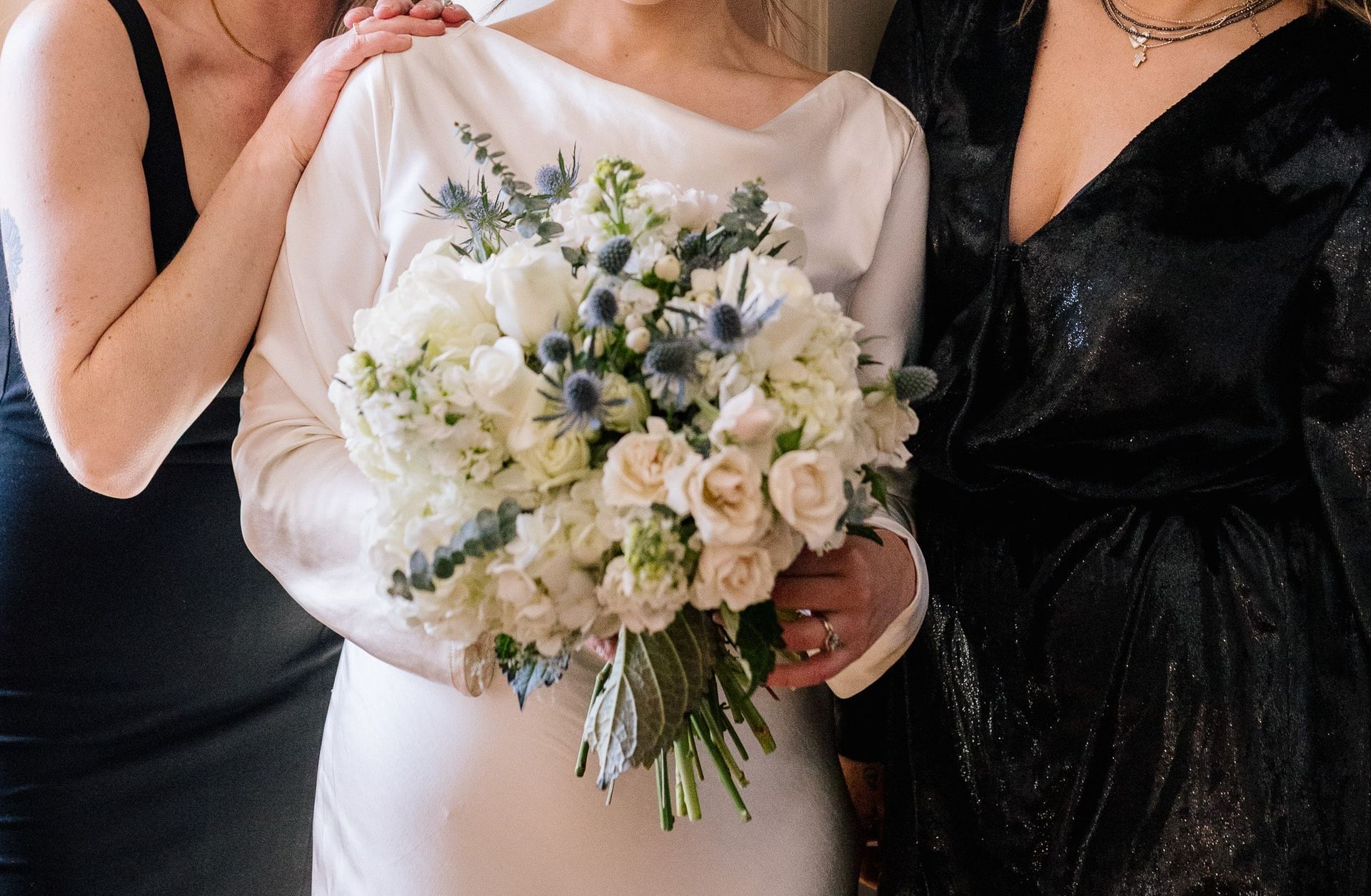 A bride in a white dress is holding a bouquet of white flowers.