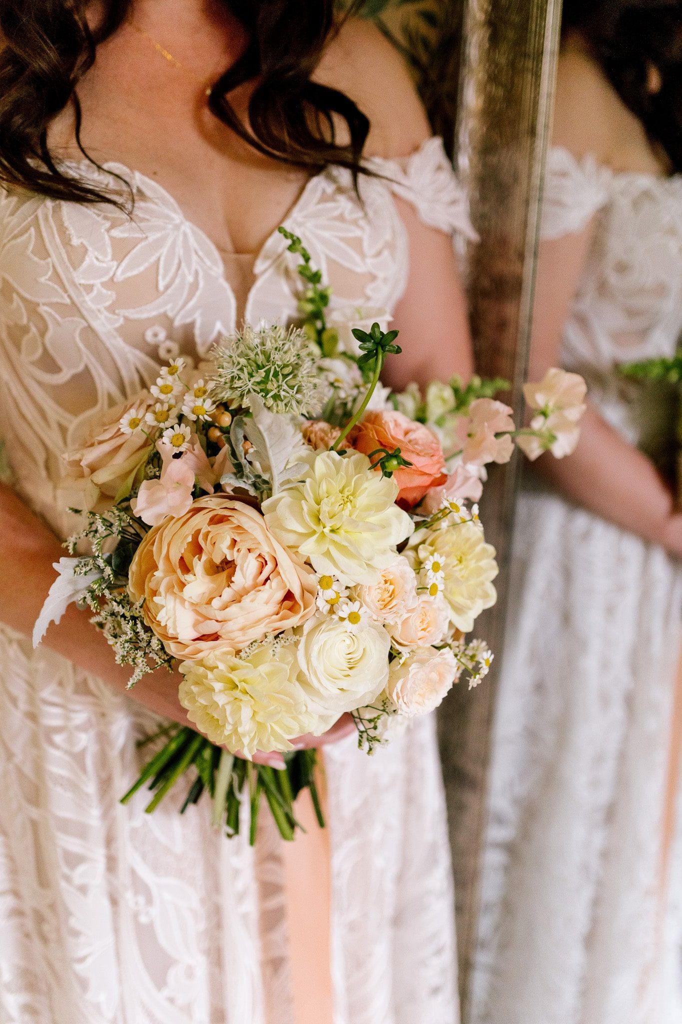 The bride is holding a bouquet of flowers in front of a mirror.