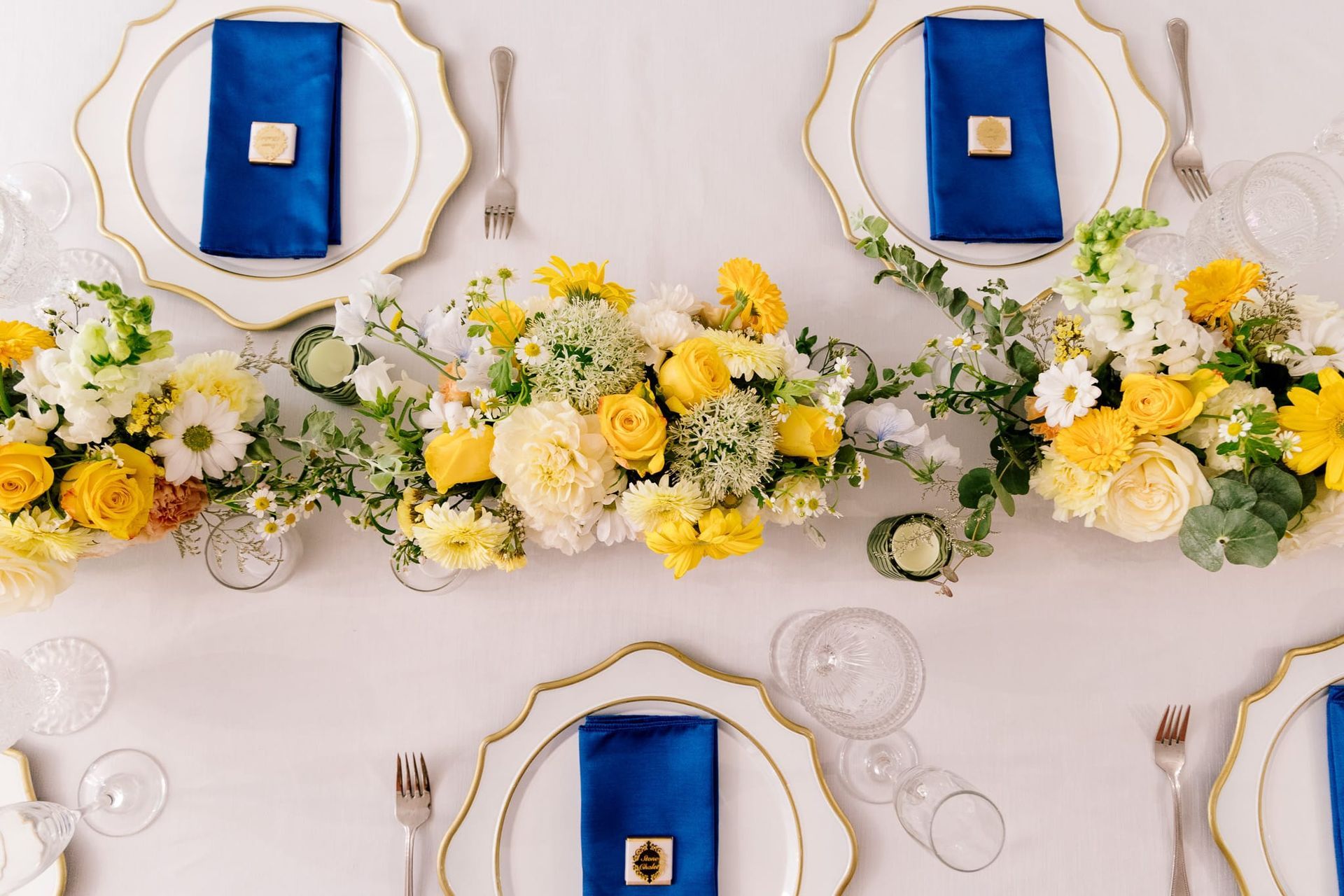 A table set for a wedding reception with blue and yellow plates and napkins.