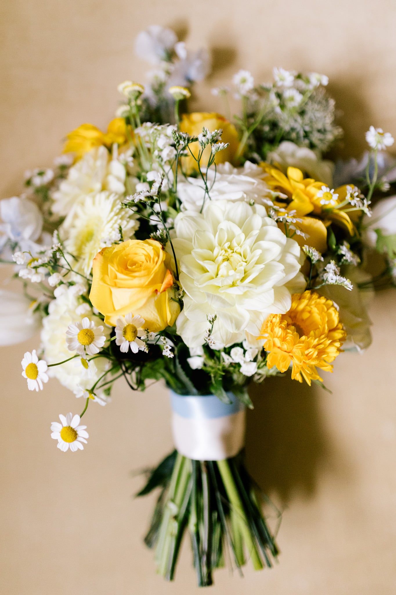 A bouquet of yellow and white flowers is sitting on a table.