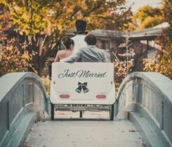 Newly married couple riding in a white carriage with 