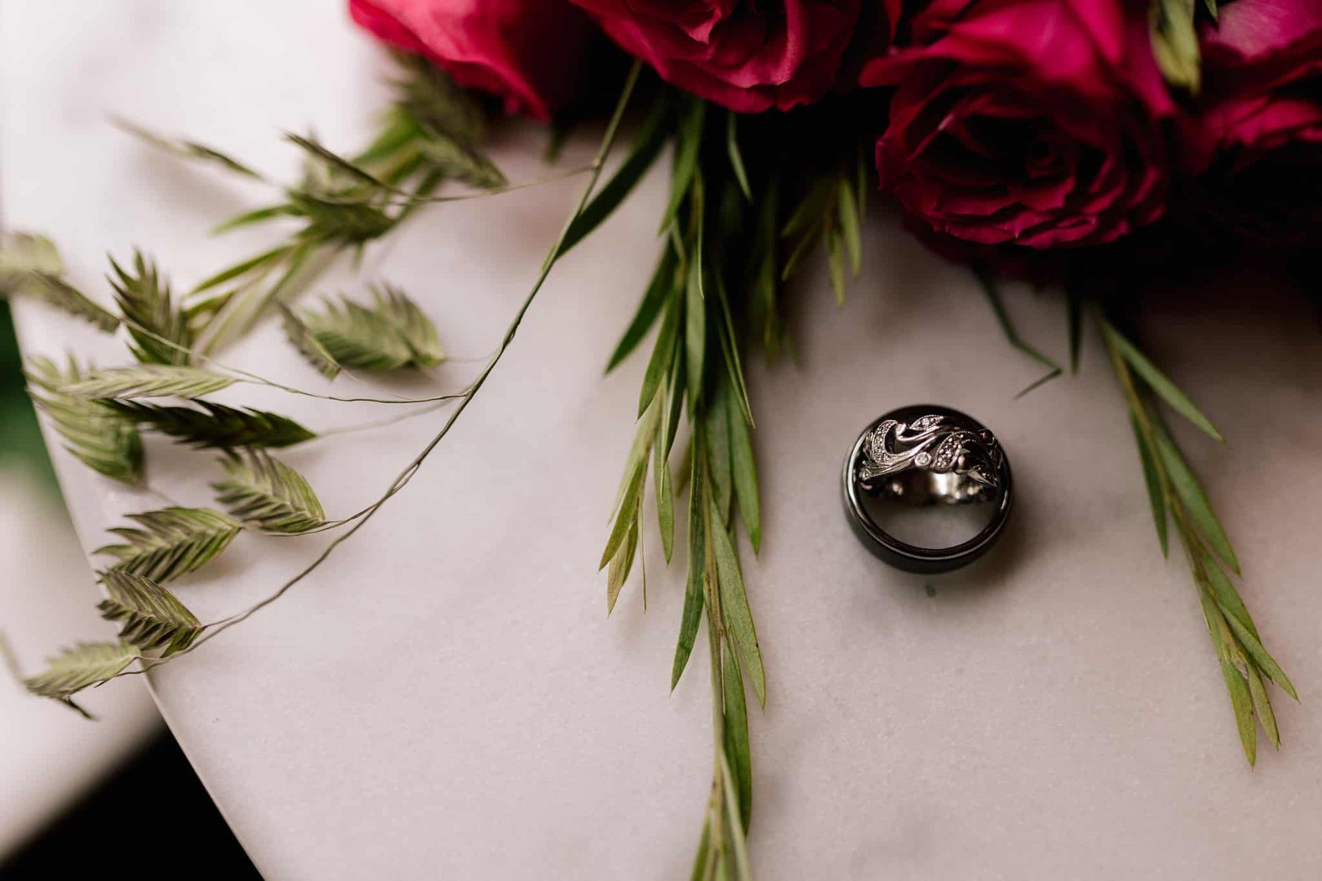 A wedding ring is sitting on a table next to a bouquet of roses.