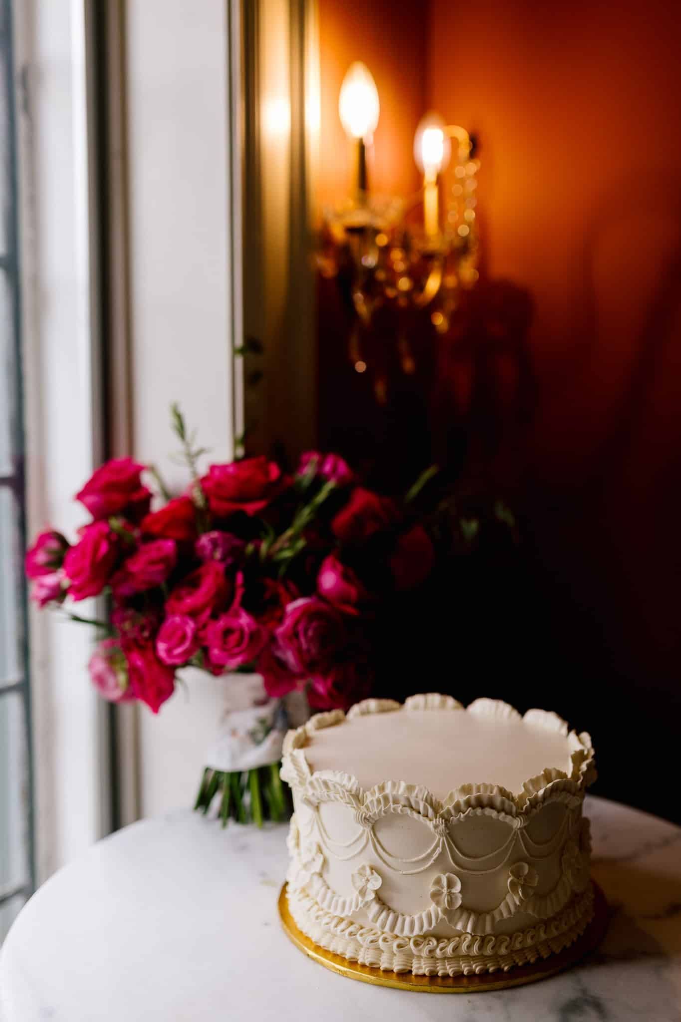 A wedding cake is sitting on a table next to a vase of flowers.