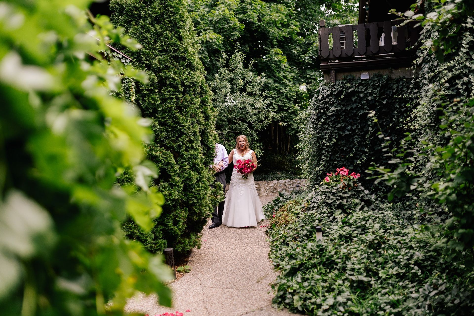 A bride and groom are walking down a path in a garden.