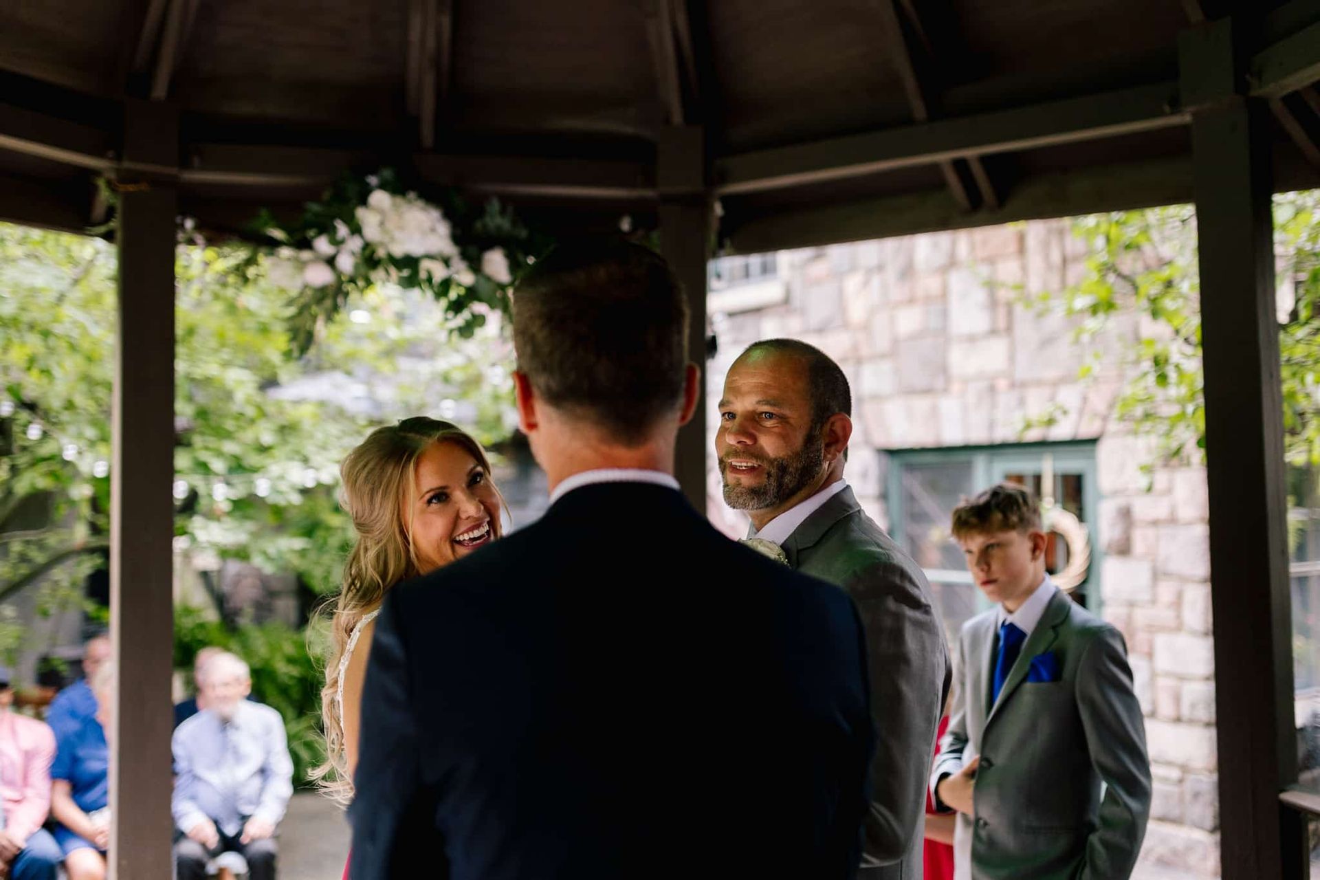 A bride and groom are standing under a gazebo during their wedding ceremony.