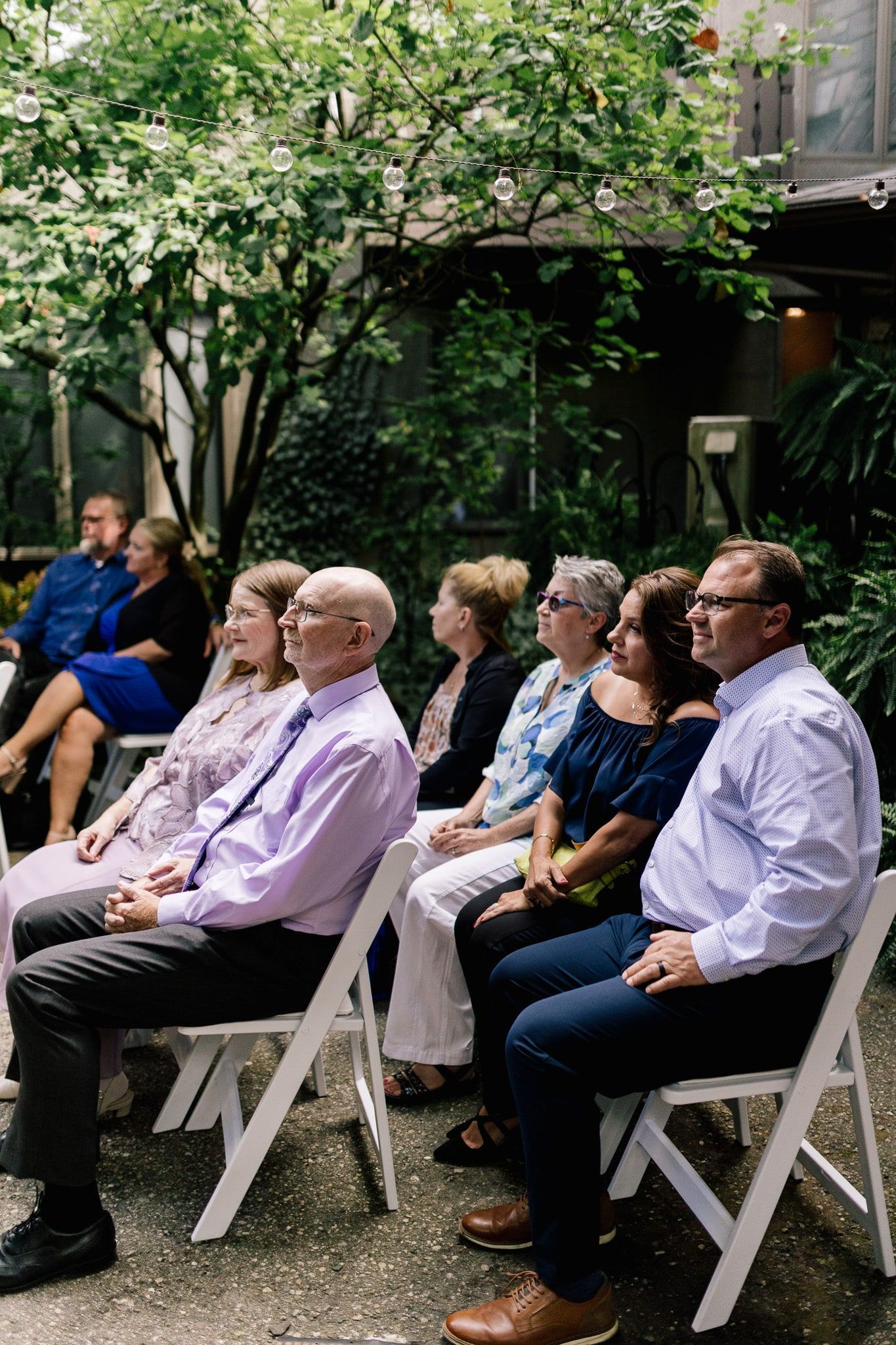 A group of people are sitting in chairs watching a wedding ceremony.
