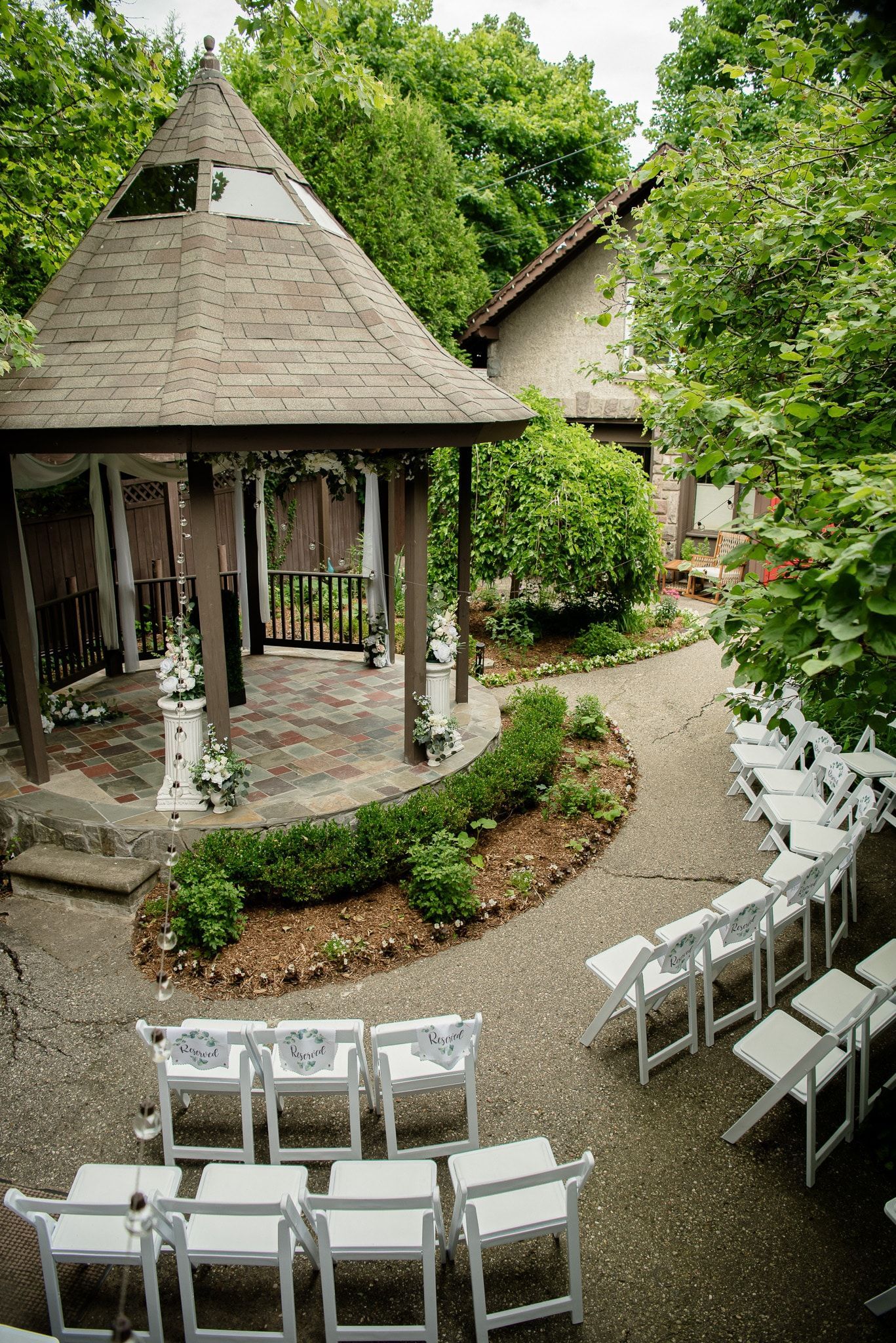A gazebo with white chairs set up for a wedding ceremony.