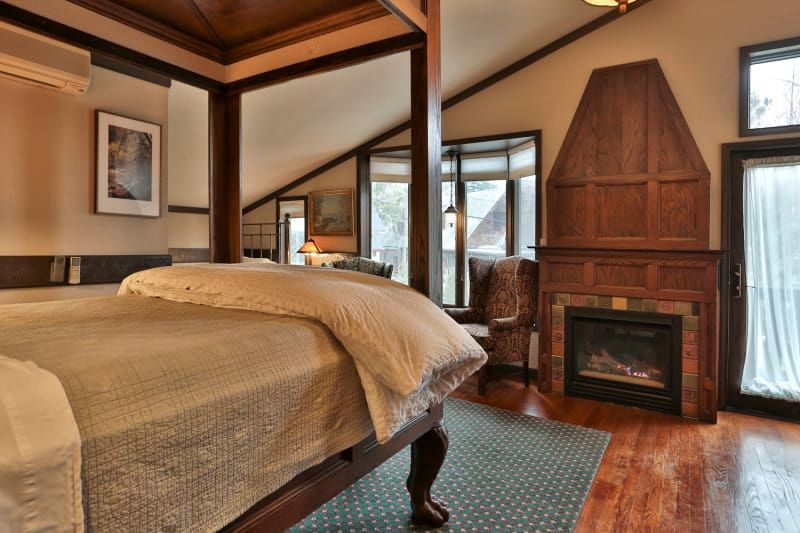 A bedroom with a four poster bed and a fireplace.