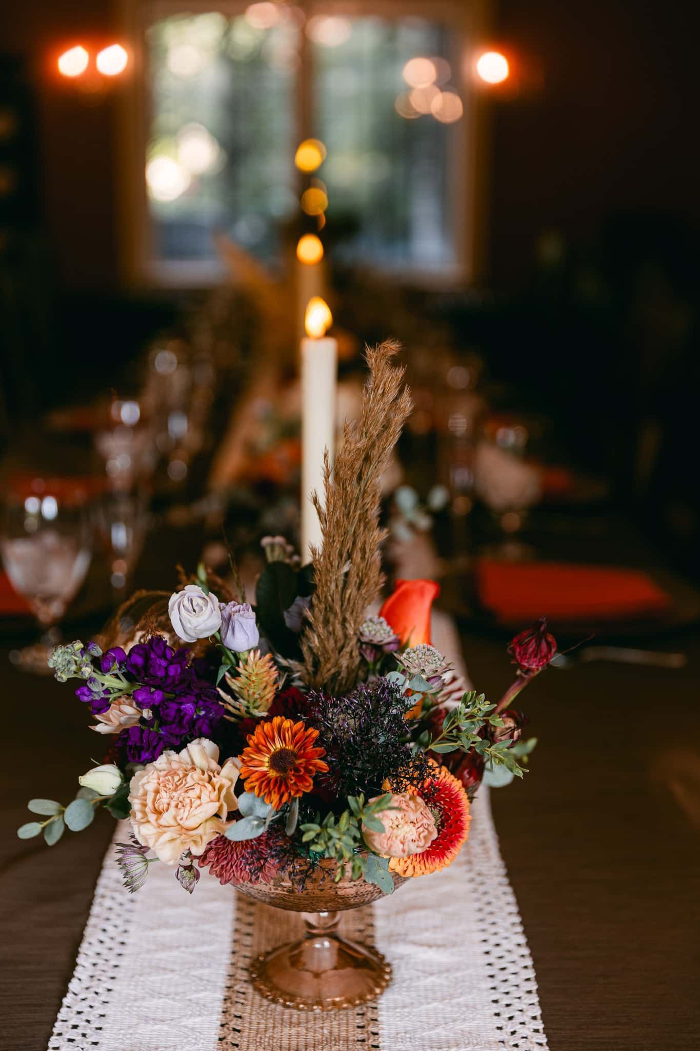 A vase filled with flowers and a candle on a table.