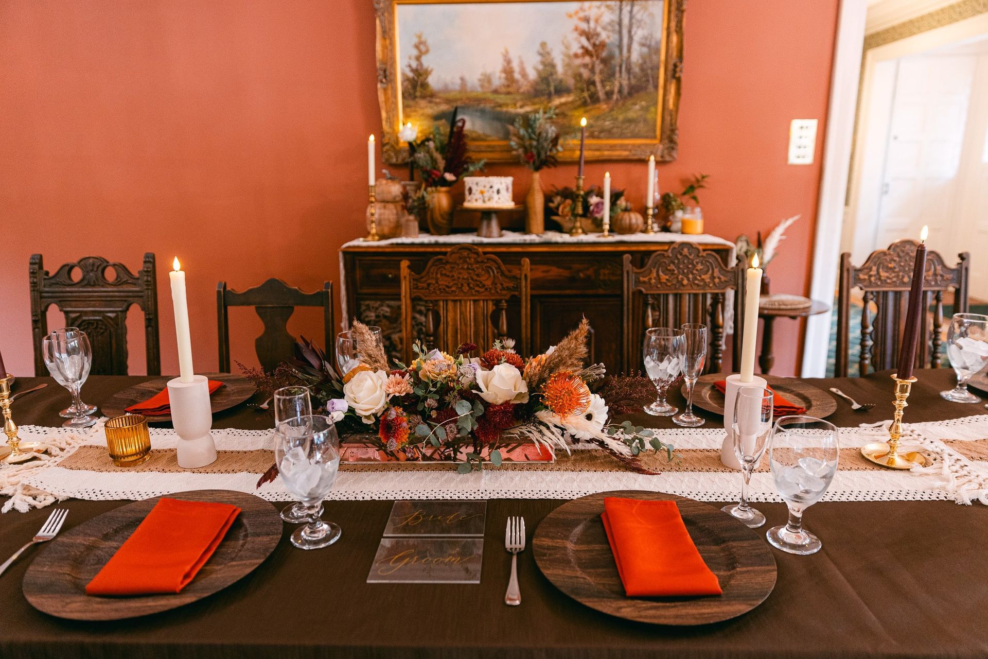 A table set for a wedding reception with plates , candles , and napkins.