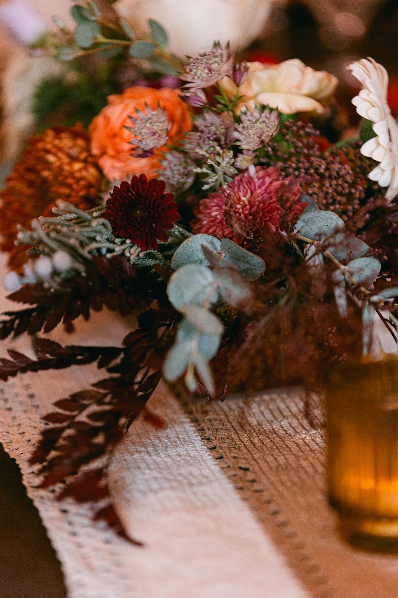 A table with a vase of flowers and a candle on it.