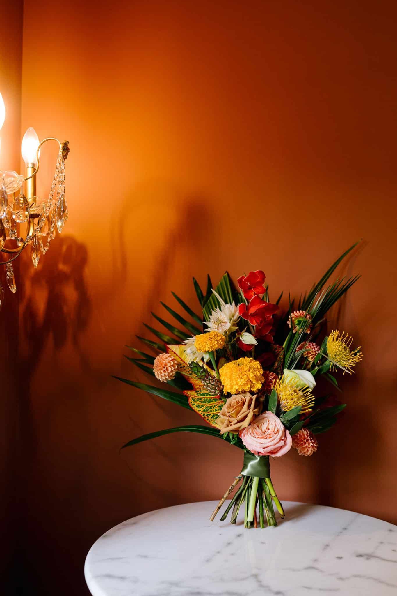 A bouquet of flowers is sitting on a table next to a chandelier.