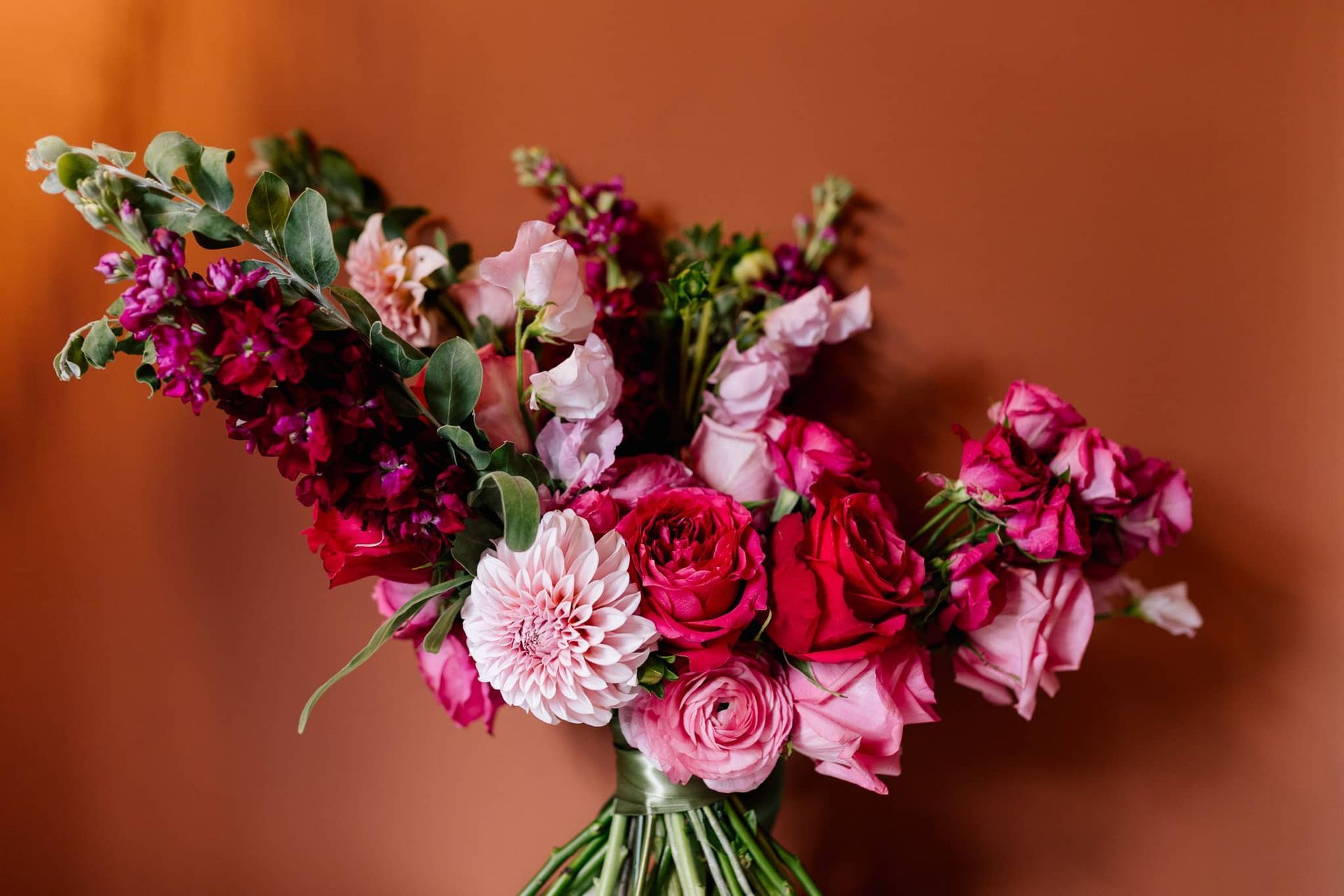 A bouquet of pink and red flowers in a vase on a table.
