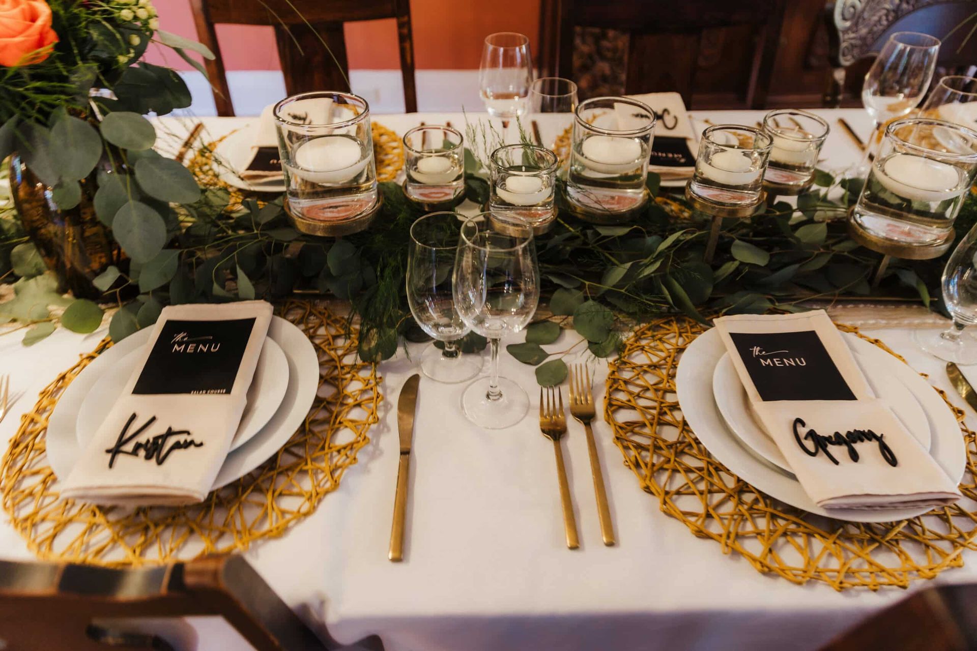 A table set for a wedding reception with plates , utensils , candles and flowers.