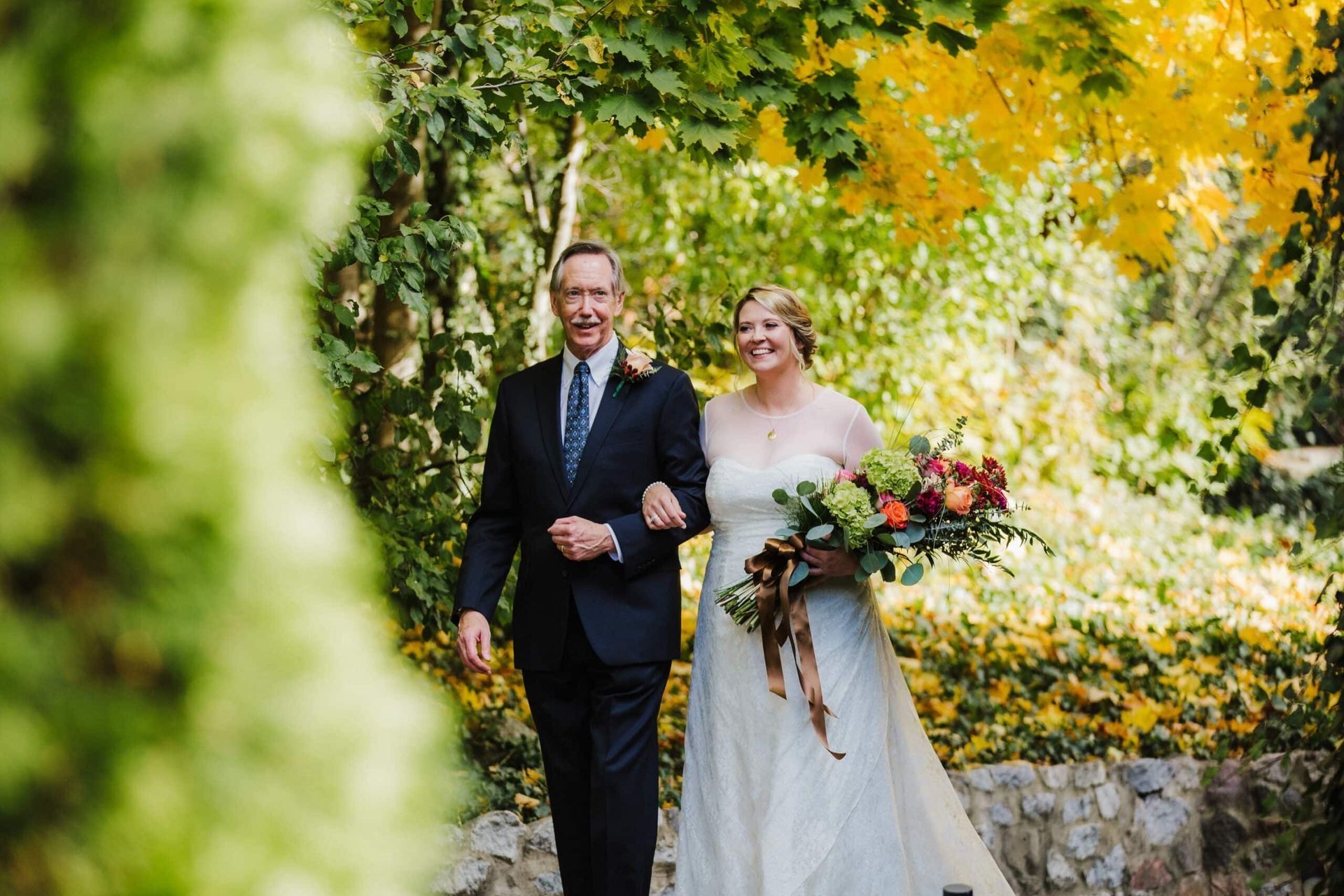 A bride and her father are walking down the aisle at their wedding.
