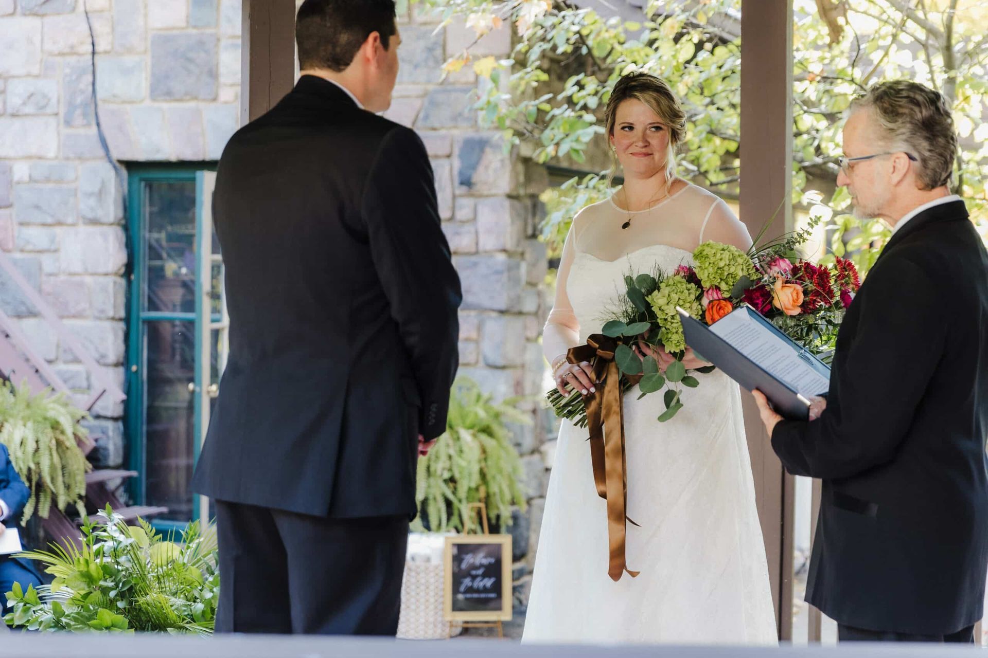 A bride and groom are getting married in front of a stone building.
