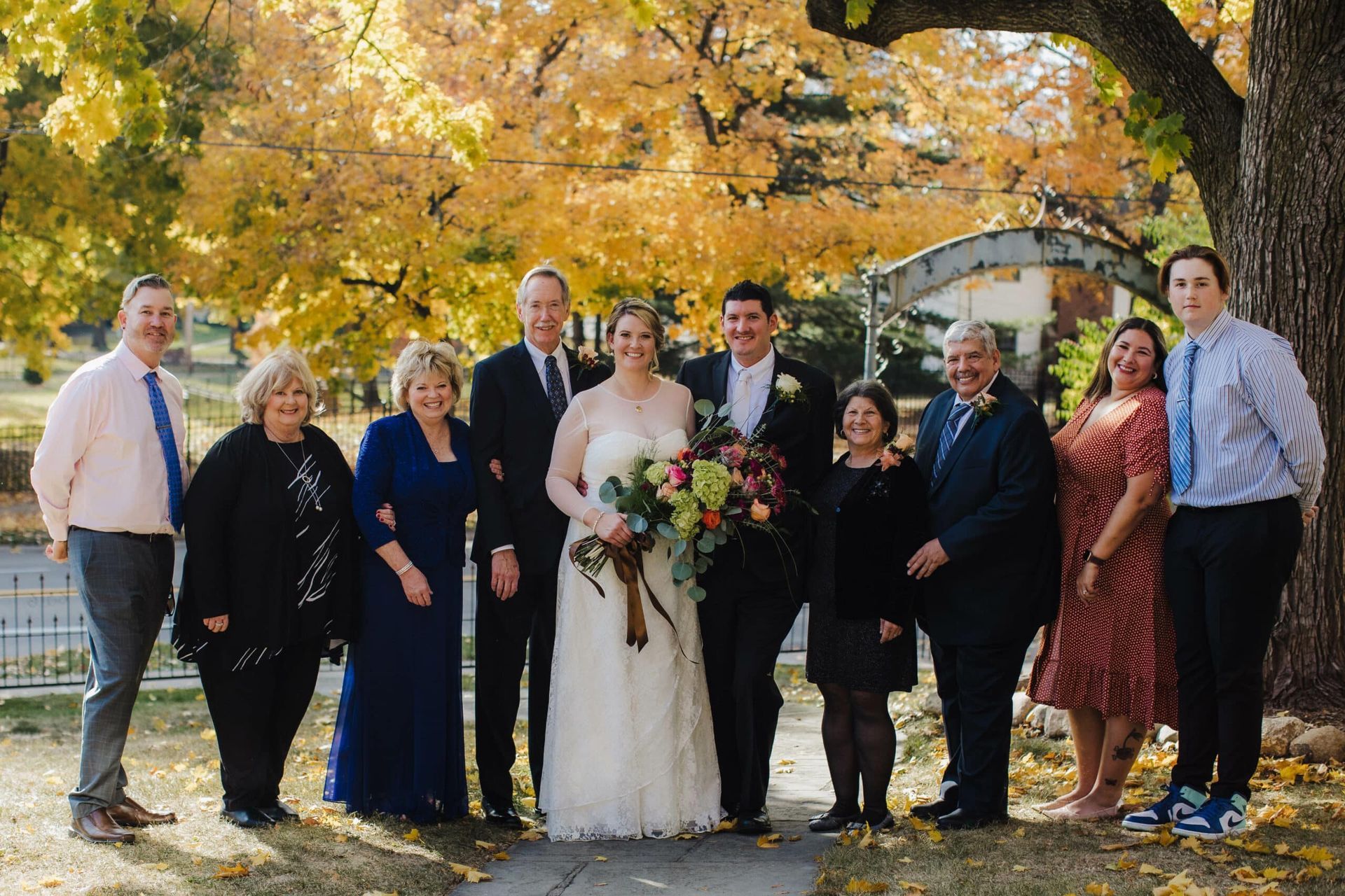 A bride and groom are posing for a picture with their family.
