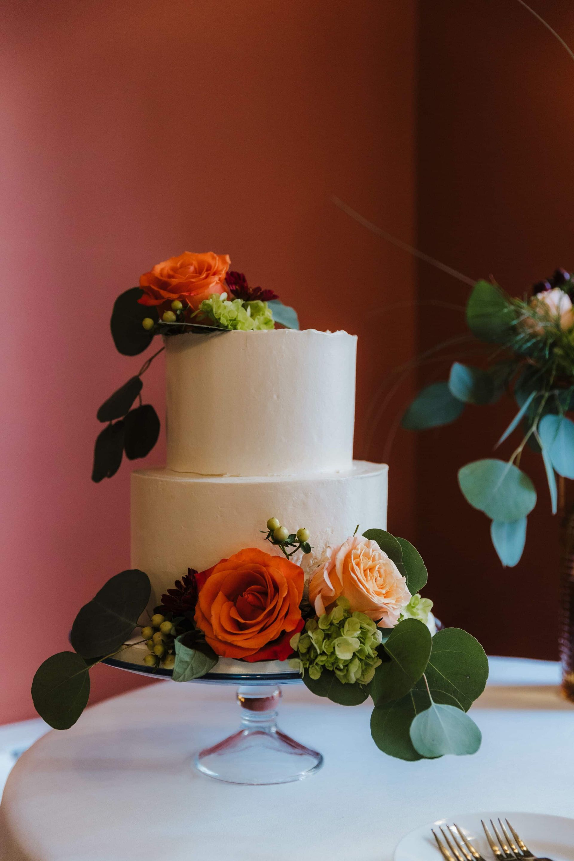 A wedding cake with flowers on top of it is on a table.