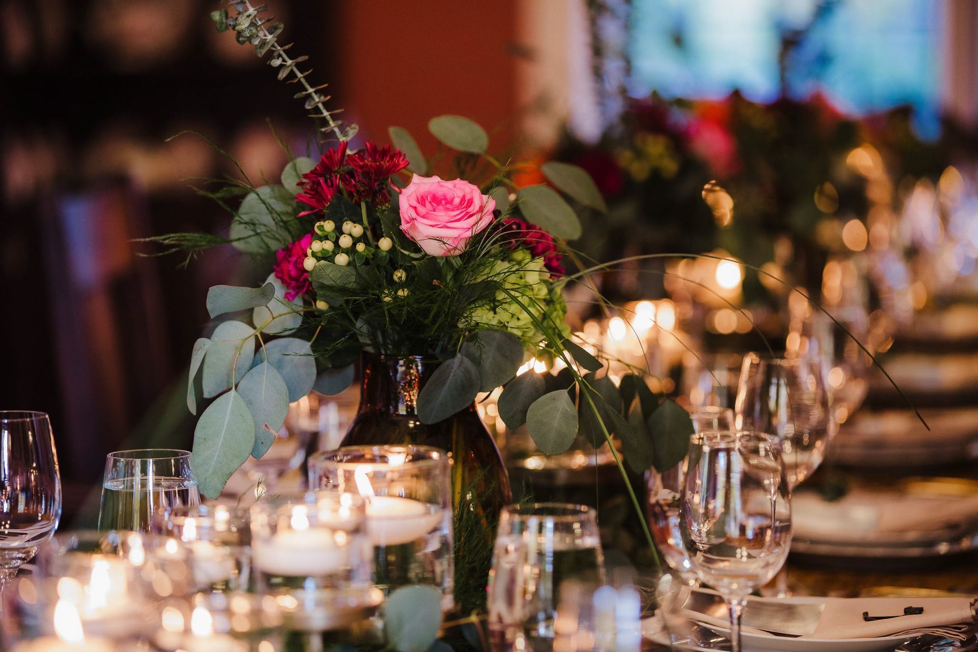A table with a vase of flowers and candles on it.
