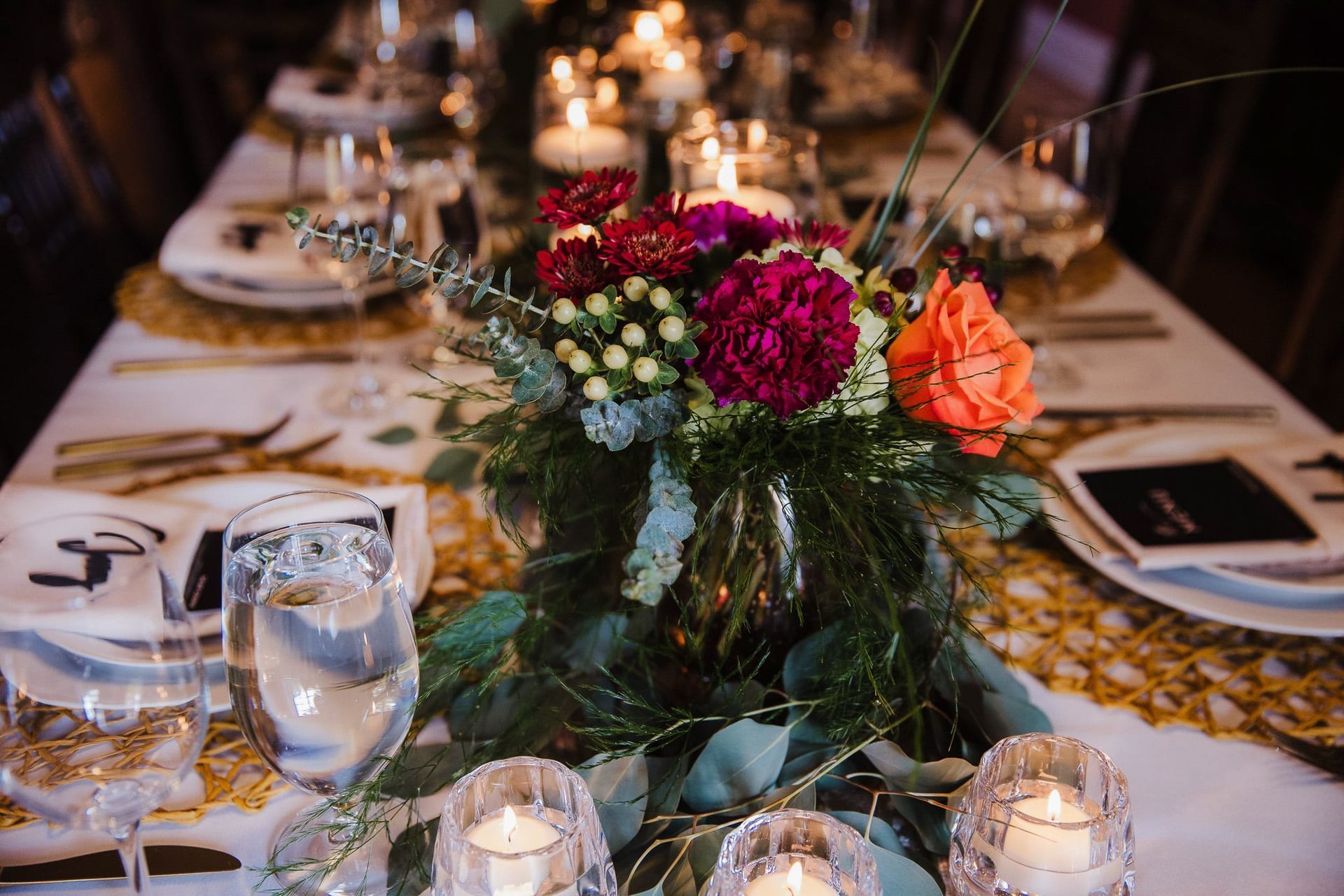 A table with a vase of flowers and candles on it.