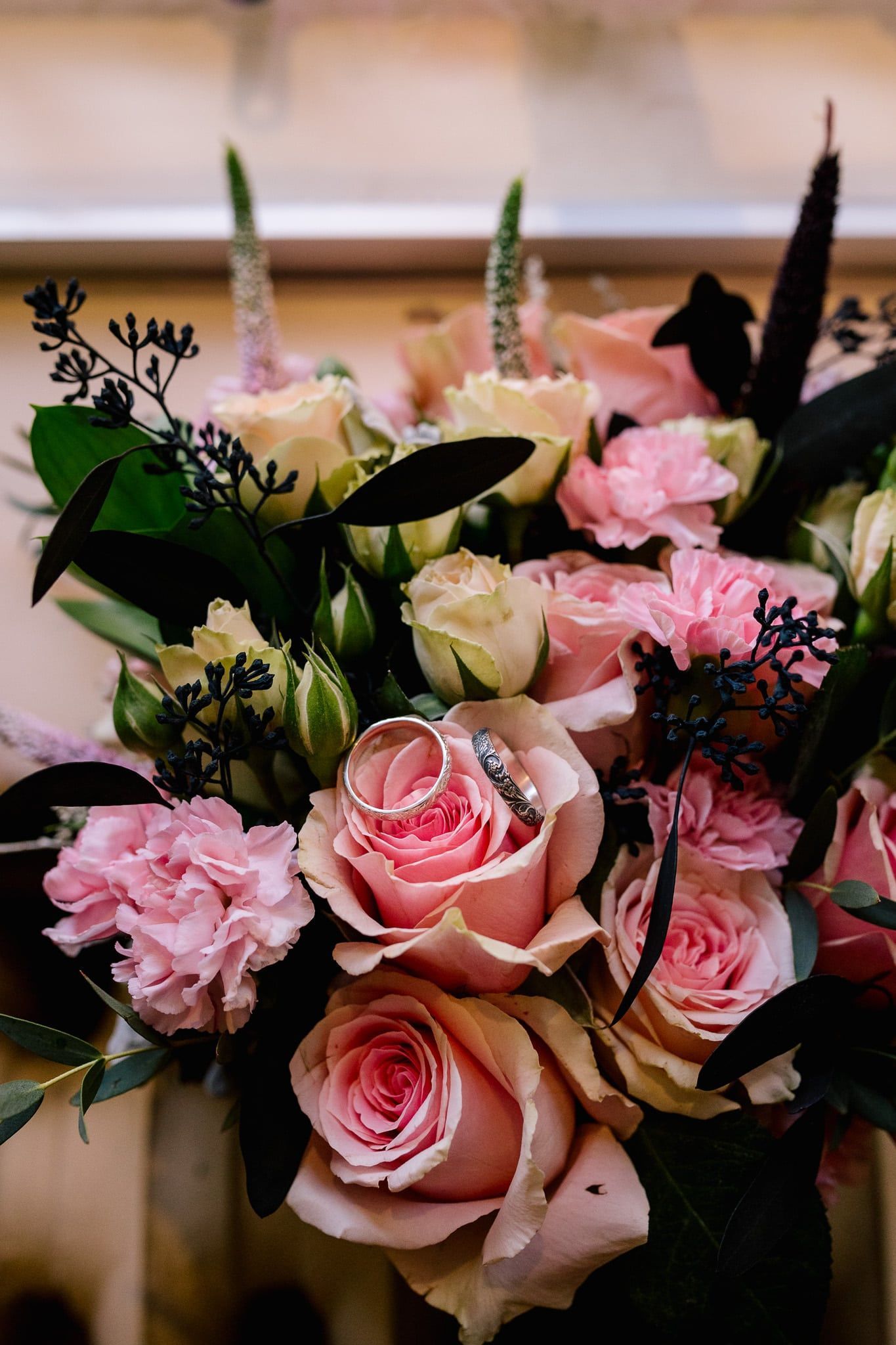 A close up of a bouquet of pink roses with a wedding ring in the middle.