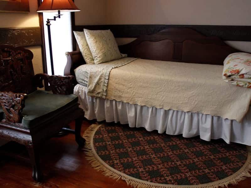 A bedroom with a bed a chair and a lamp