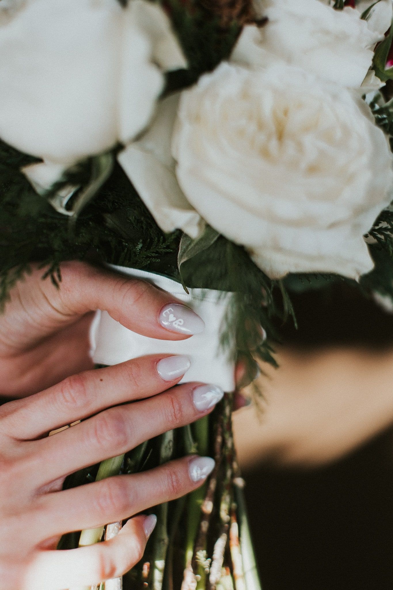 A woman 's hand is holding a bouquet of white flowers.