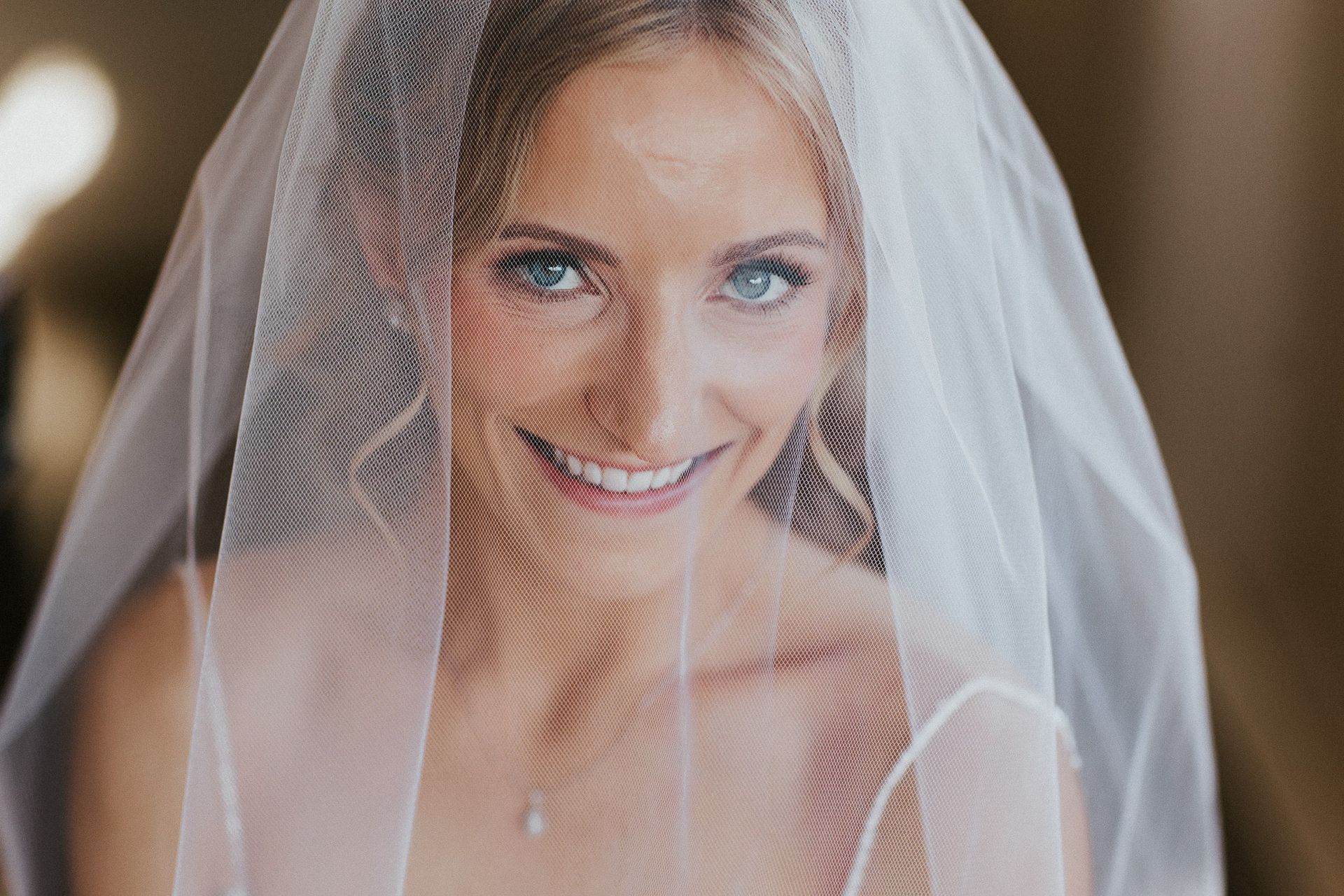 The bride is wearing a veil and smiling for the camera.