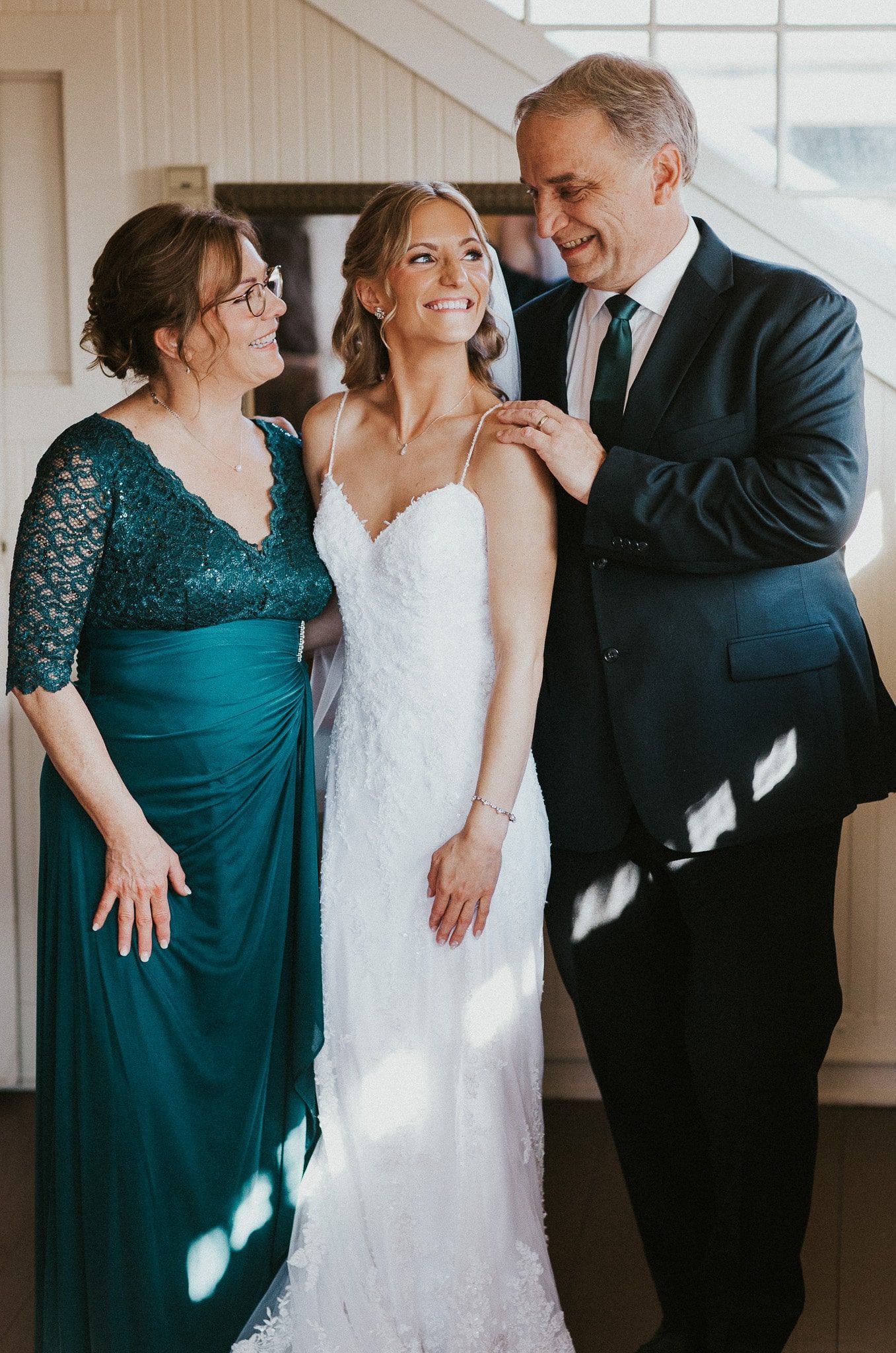 A bride is posing for a picture with her parents on her wedding day.
