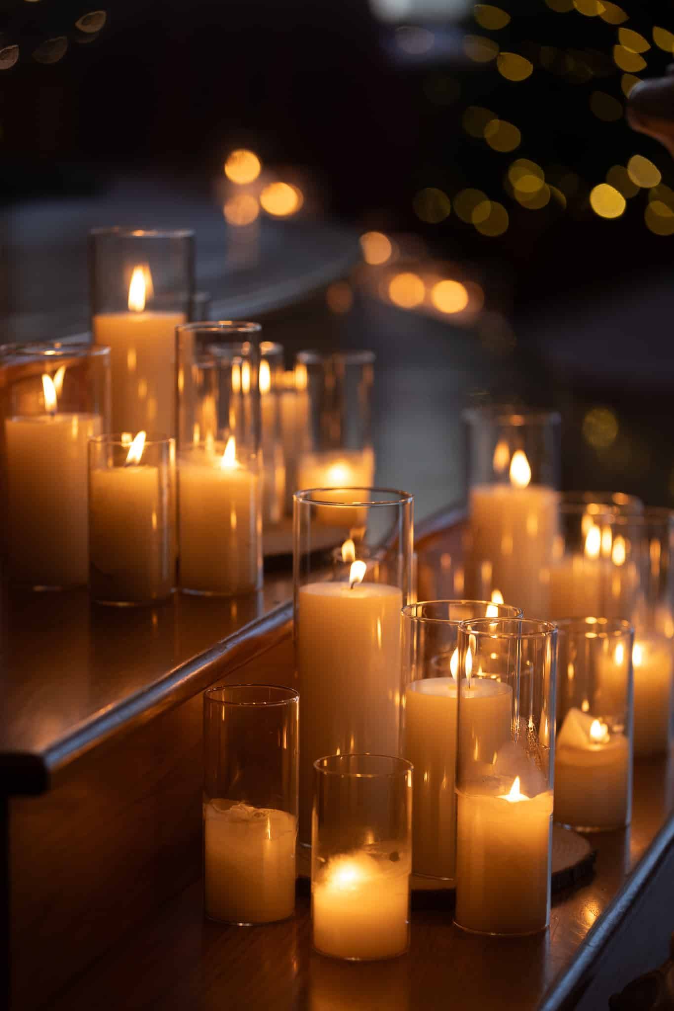 A row of lit candles in glass holders on a table.