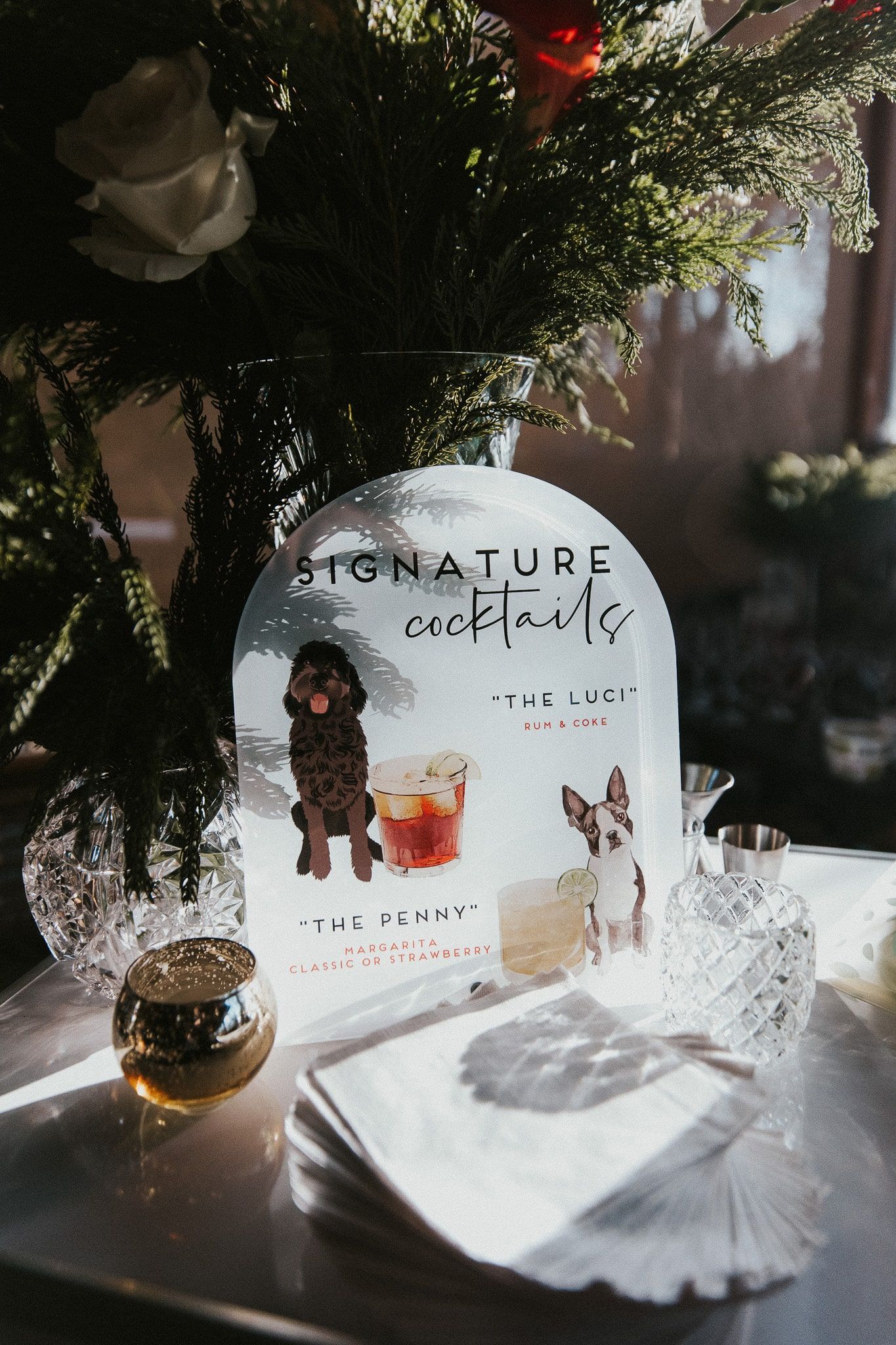 A bottle with a picture of a dog on it is on a table next to a vase of flowers.