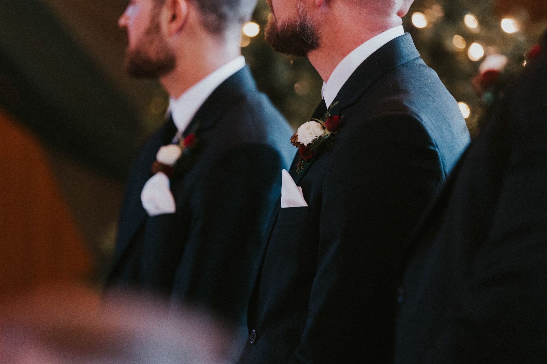 Two men in suits are standing next to each other at a wedding ceremony.