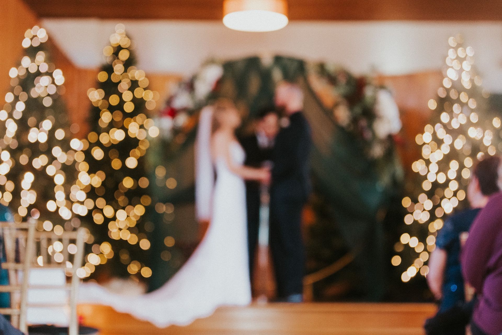 A bride and groom are getting married in front of christmas trees.