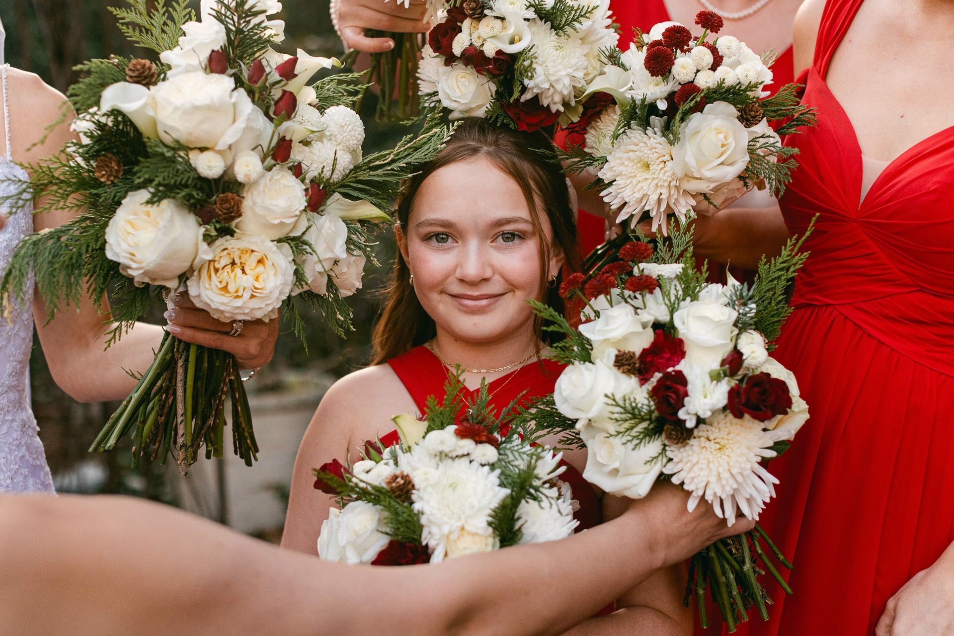 A little girl in a red dress is holding a bouquet of flowers.