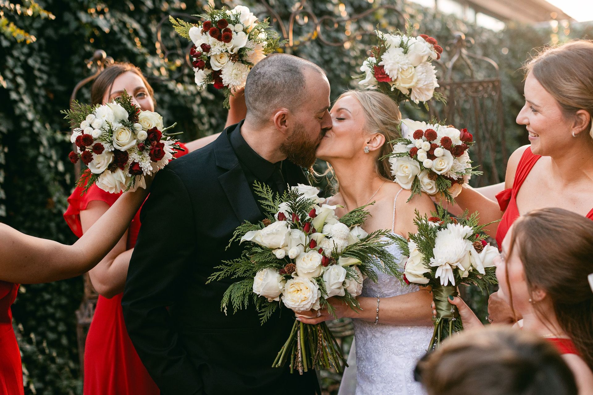 A bride and groom kissing in front of their wedding party.